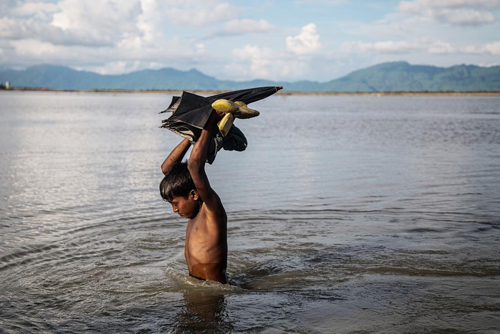 A young Rohingya boy carries some of his belongings on October 13, 2017, the morning after he arrived in Bangladesh by boat.