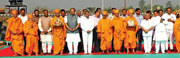 Mahant Swami Maharaj, senior sadhus and invited guests prior to the inaugural rituals of Swaminarayan Nagar Mahant Swami Maharaj ties the auspicious thread on Shri Nitinbhai Patel s wrist and