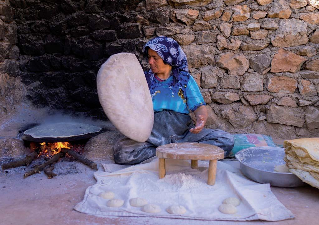 Women cook in round flatbreads in clay ovens.