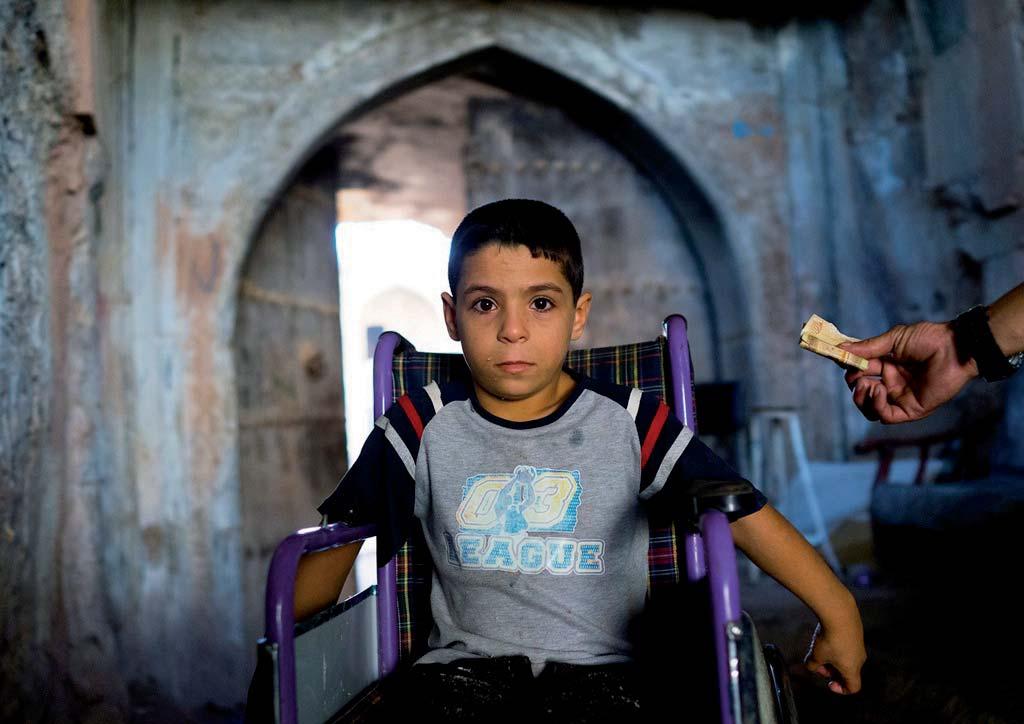 Koya. A young boy in a wheelchair rolls through the streets.