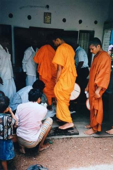 16. Two laymen pour water over the monks feet and pat them dry with a towel. The monks enter the house walking on a strip of white cloth. The most senior monk sits next to the temporary altar.