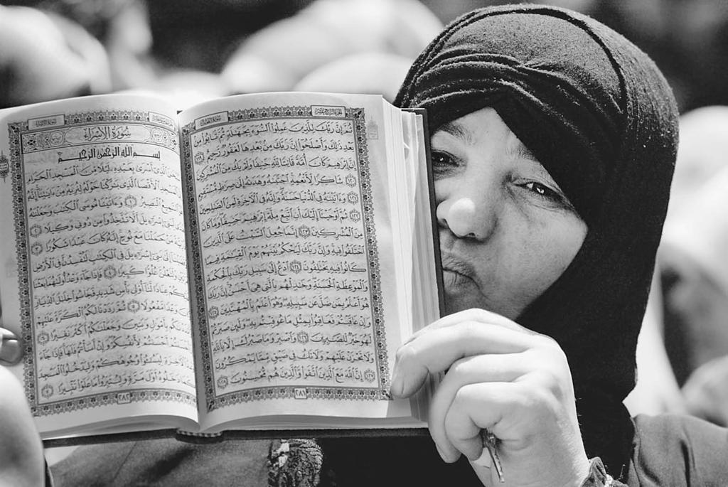 A Muslim woman holds up a copy of the Qur an in Arabic. The Qur an was revealed to the Prophet Muhammad by the angel Jabra il over a twenty-three year period in the seventh century.