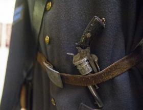A pistol is secured in the belt of a Confederate uniform on display at the