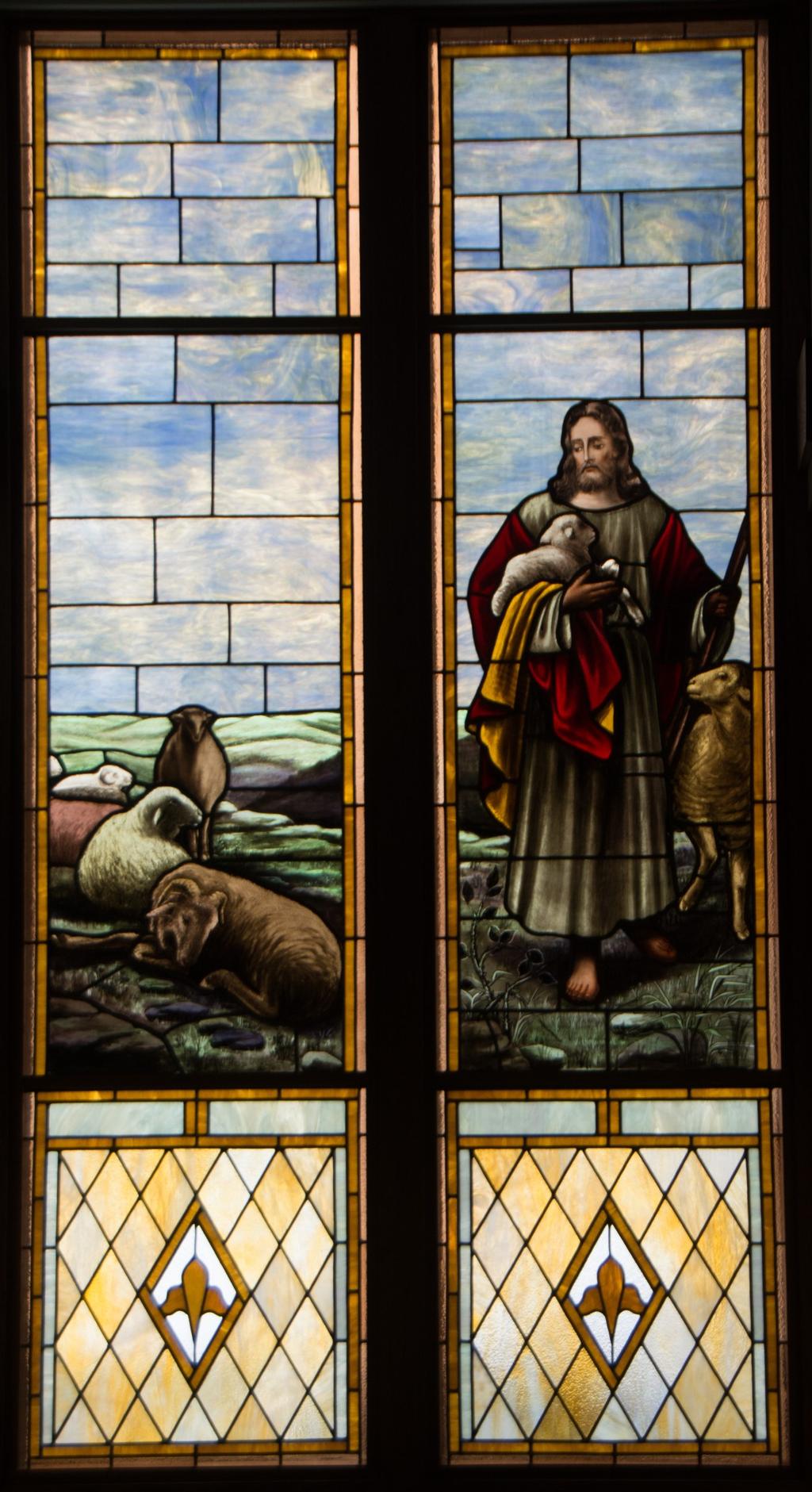 JESUS THE GOOD SHEPHERD As you face the Altar in the center aisle of the church, the first window to your left (east) is the comforting picture of Jesus The Good Shepherd.