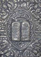 The outside is covered with thin silver plates decorated with floral patterns and geometric shapes, and with the Ten Commandments etched on the Tablets of Law.