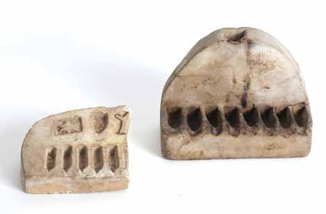 This is the left part of an interesting Chanukah lamp made of a flat rectangular stone. Has five cornets, a shamash, decorated by a Star of David and the remnants of another decoration.