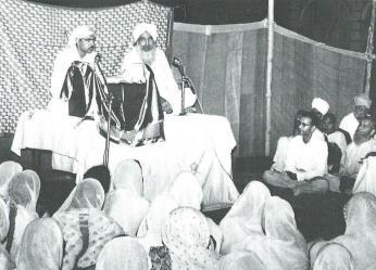 A figure in white wearing a white turban, and with a grayish-white beard, had appeared surrounded by a small crowd of excited people.