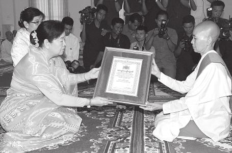 Daw Nan Shwe Hmon, wife of Vice- President Dr Sai Mauk Kham, presenting certificate and insignia to a laywoman.