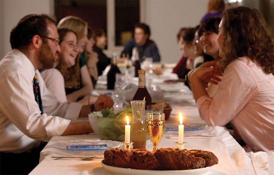 Photo courtesy of: Get Shabbat. This image shows a Jewish family enjoying their Shabbat dinner. At the front of the photo you can find a Challah (which is a traditional Jewish bread) with raisins.