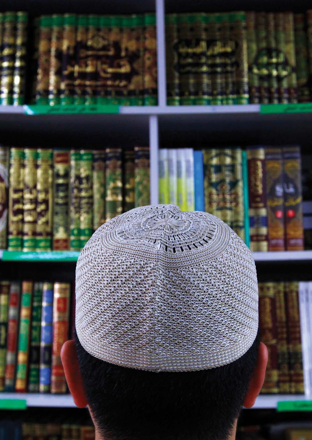 A man wearing an Islamic prayer cap, or Kufi, looks at Islamic books on display at a