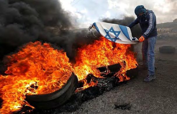 6 Right: A masked Palestinian burns the Israeli flag during a riot in Judea and Samaria (Palinfo Twitter account, March 17, 218).