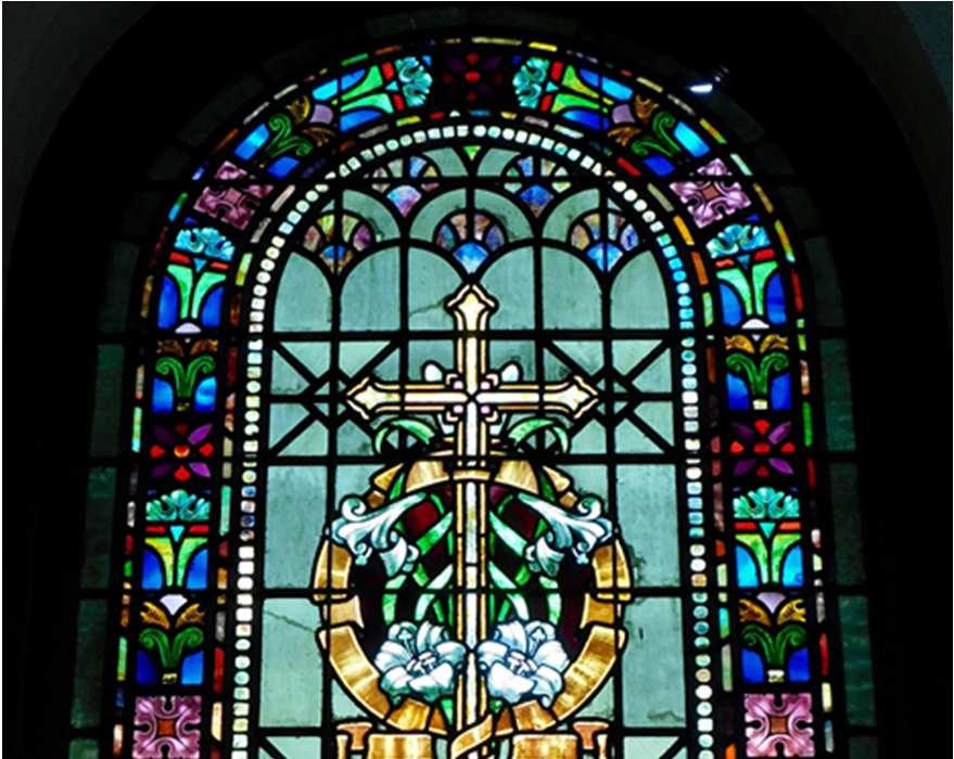 EASTER CROSS The Dempwolf window celebrates the Resurrection with a plain cross and Easter lilies symbolic of joy, life and hope. J. A.