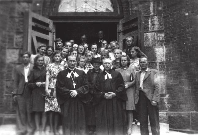 3. the nazi occupation Pastor Kalvanas and Pastor Baltris with the Tauragė and Kretinga church choirs before the Kretinga church doors, 1943. Pastor Kalvanas wears a silver cross. JKA.
