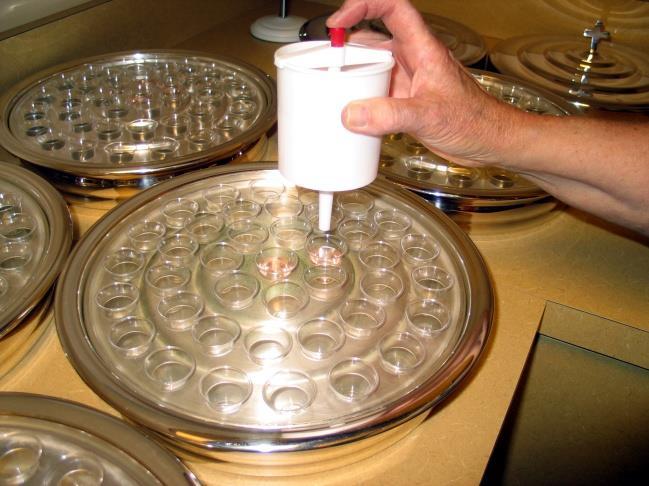 Partially fill 4 of the center individual cups in all 20 or more of the communion trays, with the alcoholic-free wine. 4. Remove the bottle of consecrated red wine from the small refrigerator.