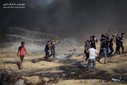 3 Right: Young Gazan rioters pull at a coil of barbed wire near the security fence in eastern Khan Yunis.