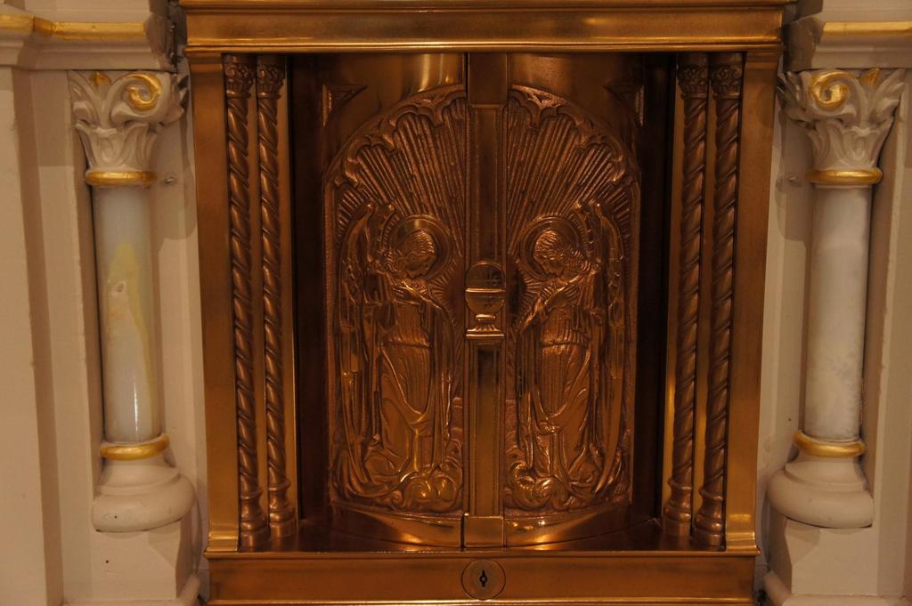 14 The altar of reservation is structured around the tabernacle, the glistening brass compartment which contains the blessed sacrament.