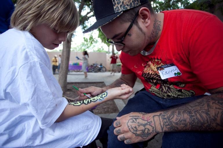 Coalition for the Homeless Fall Festival Kenny, a Valencia student, offers his artistic skills to a youngster at the Coalition.