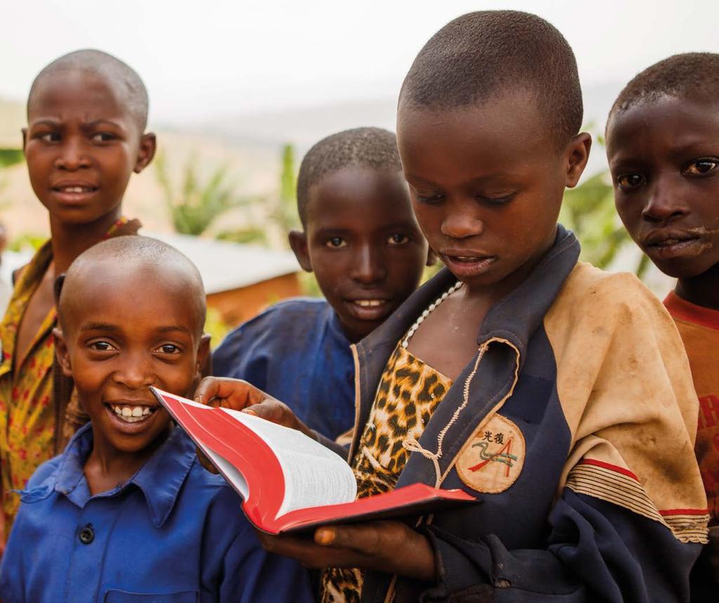 Rwandan children with a Bible given to them as part of the End-to- End program, which provides Bibles to people who have taken part in Scripture listening groups.