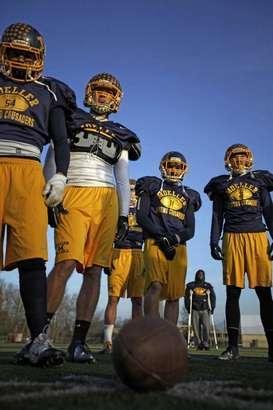 Some of the Archbishop Moeller High School Crusaders Football team listen to their coach talk strategy for their upcoming game Saturday against Toledo Whitmer for the State Title, to be played in