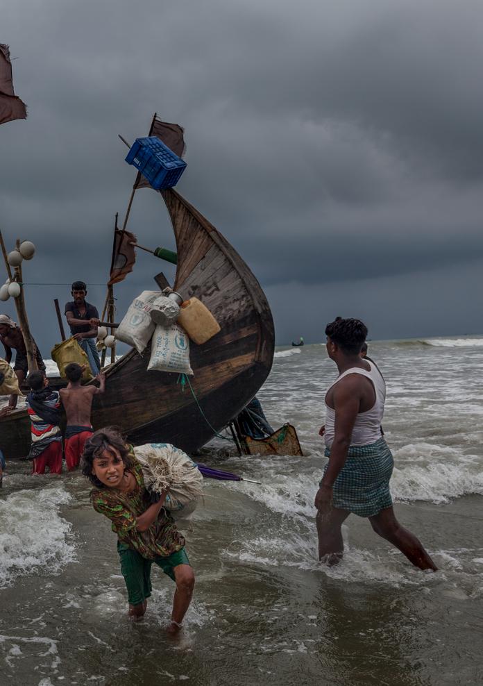 Noor Haba, 11, carries her family's belongings to Shamlapur Beach in Bangladesh after the boat she