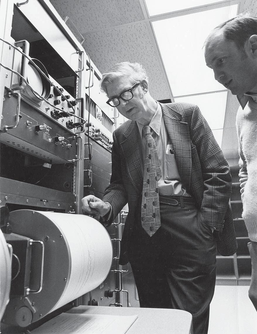 Drs. Kenneth L. Cook (left) and Robert B. Smith (right) examining a helicorder record in Room 720 of the W. C. Browning Building (the original network telemetry lab of the Seismograph Stations).