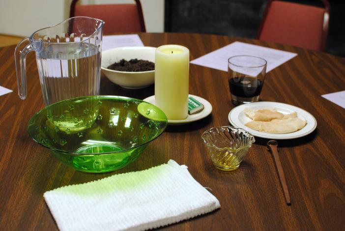 ITEMS IN THE CENTER OF EACH TABLE Candle with matches Towel, empty bowl, small pitcher of water Pita bread, cup of grape juice Bowl of earth with small stones