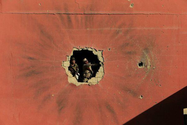 Alaa Al-Marjani / Reuters Policemen look through a hole in a