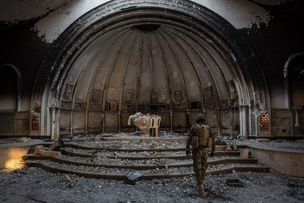 Chris McGrath / Getty A fighter from the NPU (Nineveh Plain Protection Units) walks through a destroyed church on November 8, 2016 in