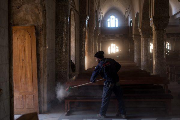 Chris McGrath / Getty A man sweeps dust off pews in preparation for the