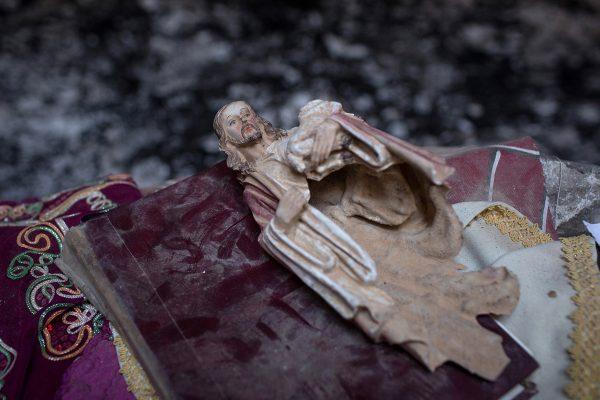 Chris McGrath / Getty A smashed statue of Jesus Christ sits on the altar of a church burned and destroyed