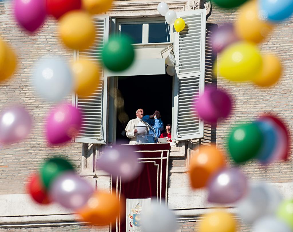 OUVREZ LES PORTES! Pope Francis looks at the newly released balloons, which remained caught in the window during the Angelus noon prayer in St. Peter s Square at the Vatican. M.