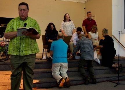 Tim Irwin gives a charge to the candidates during the footwashing portion of the ceremony; (Upper Left) The candidates are prayed for by the ordained ministers present.