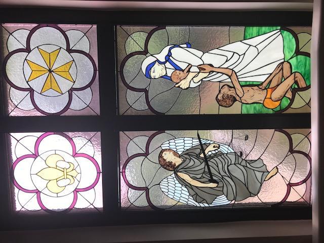The sixth window represents Care for the Sick. On the left, Saint Michael the Archangel is depicted because he is the patron of the sick.