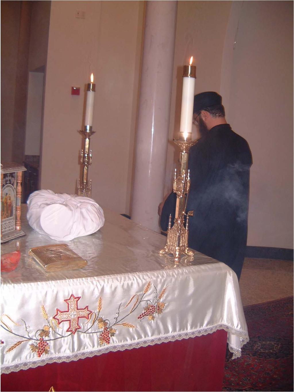After putting the spoonfuls of incense, the priest takes the censer and makes three complete processions around the altar and the deacon