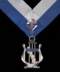 His Jewel is Cross Keys, which represents responsibility for the safe keeping of the funds, suspended from a blue ribbon. He wears a white cincture with silver fringe.