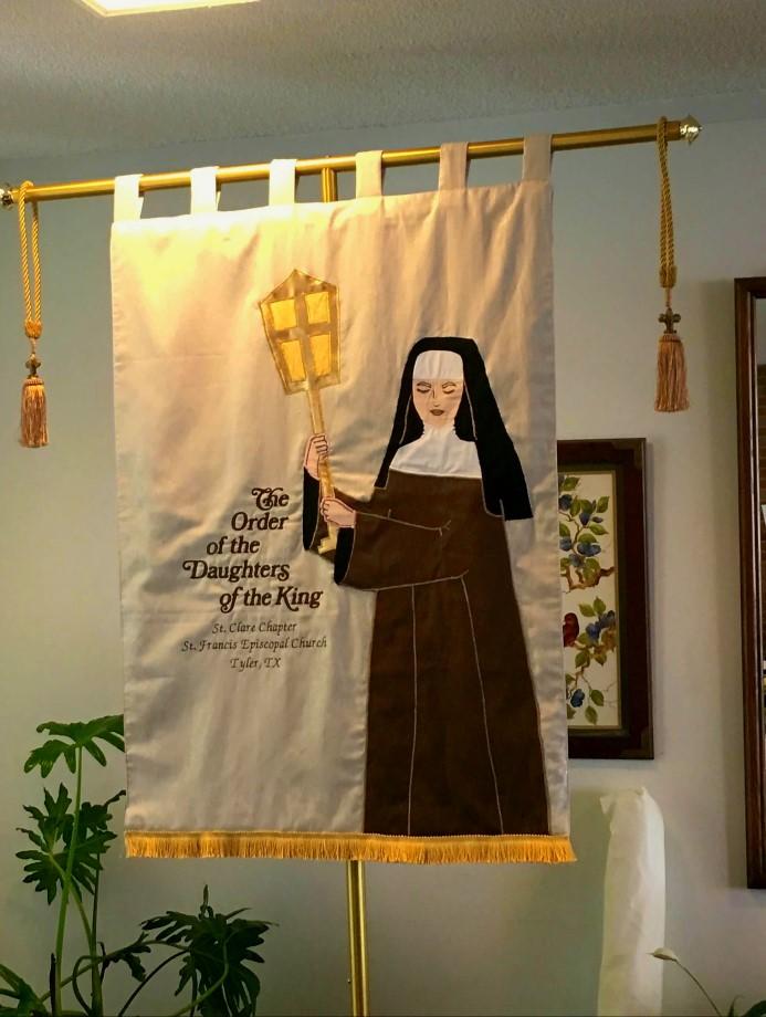 The banner was created from drawings and historical information which developed into an artistic fabric interpretation of St. Clare. Pieces of fabric were appliqued onto the backing material.