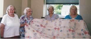 Upper Picture: Holding the Redwork quilt made by Rowena Mc- Falls are (L-R): Judy Pat Williams, Merita England, State Society Second Vice President
