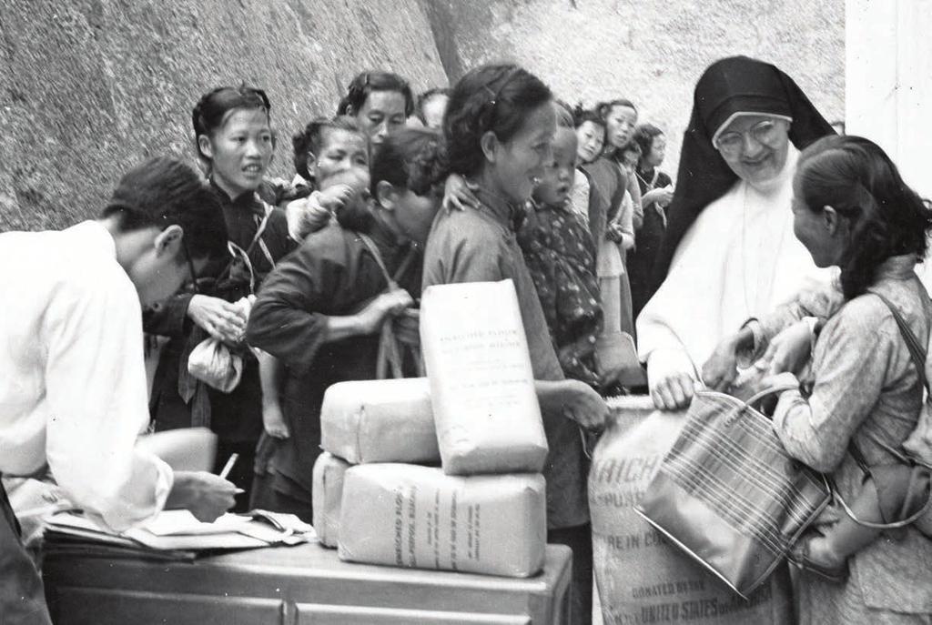 Sister Moira Riehl, M.M., distributes rice and flour to refugees at King s Park in Kowloon, Hong Kong in the mid-1950s.