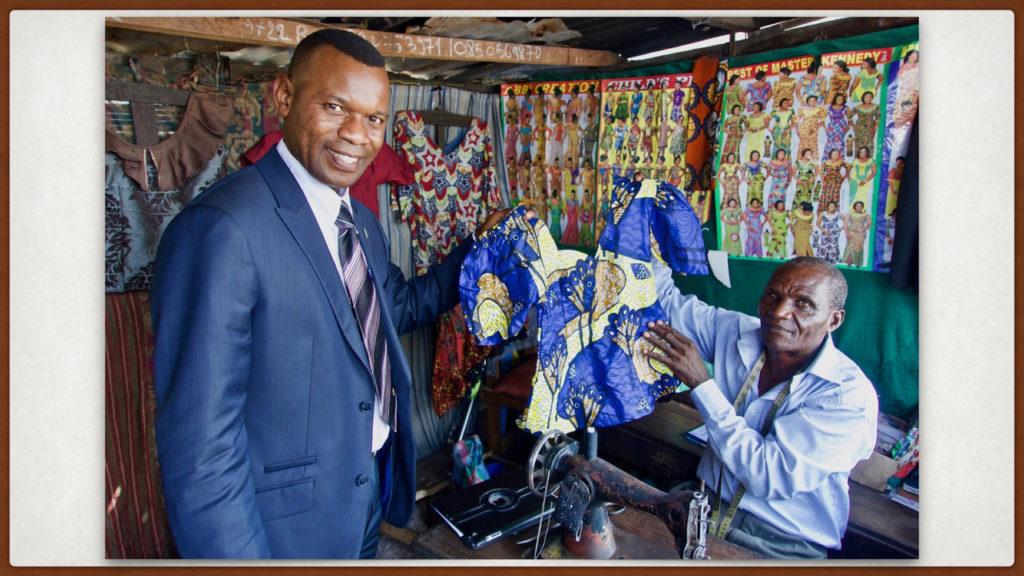 David is very talented. He holds up a child s garment with President Ephraim Zola, at that time a counselor in our stake presidency. President Zola is wearing a suit that David made for him.