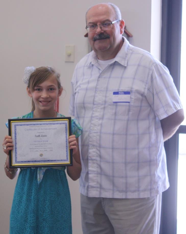 Faith Lewis, daughter of Scott and Bernadette Lewis, receives the award for winning the Knights of Columbus Substance Abuse Awareness Poster Contest with a lively entry.