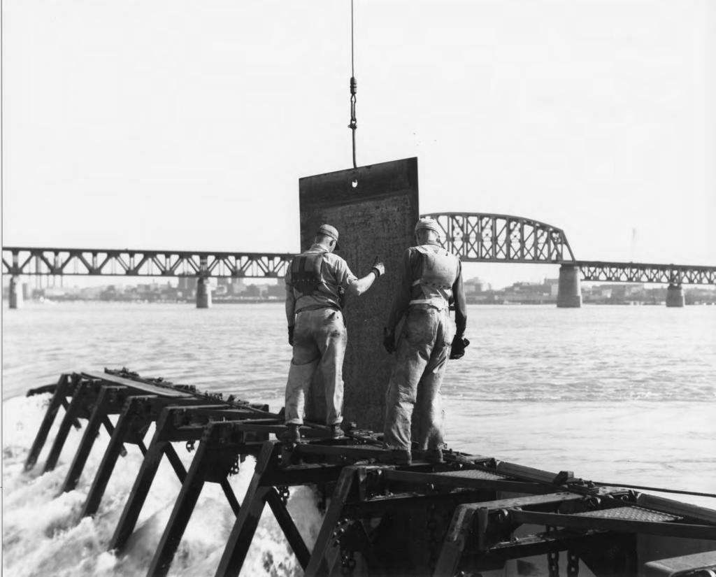 (Corps of Engineers) Workers guide the metal shutter down the front of the Boule