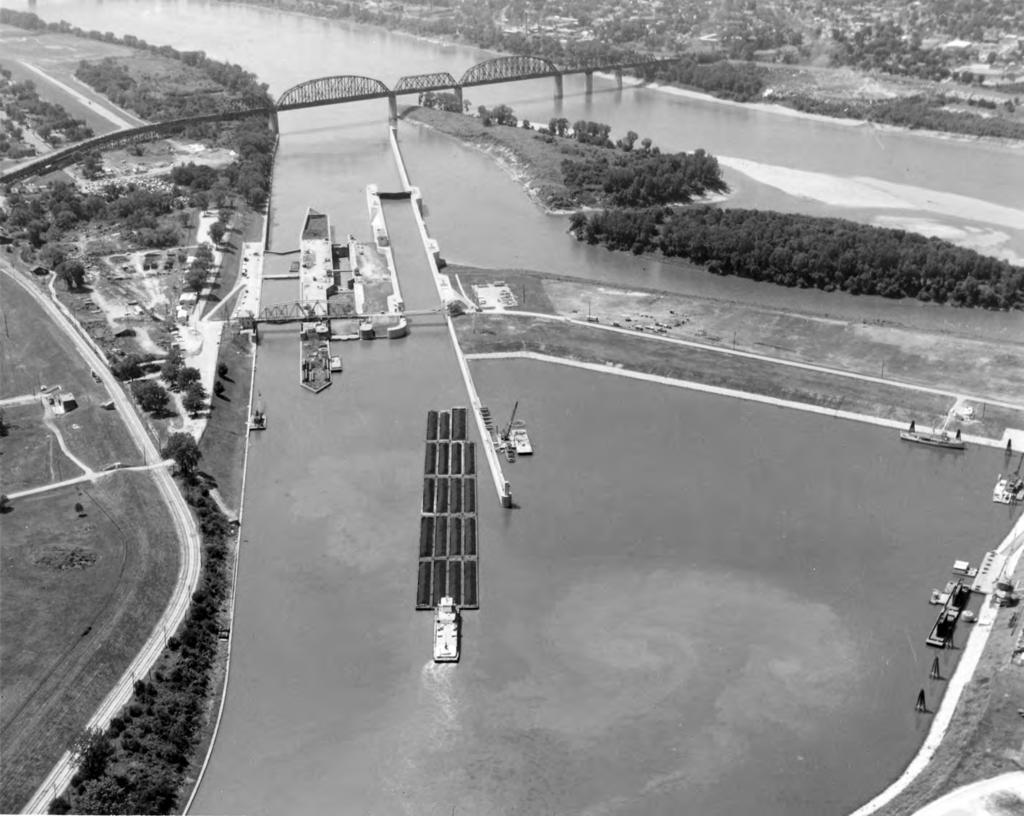 Triumph At The Falls: The Louisville and Portland Canal Aerial view of a 19-barge tow entering McAlpine Lock; left of the 1200-foot lock are the 360-foot Scowden Locks and Lock 41.