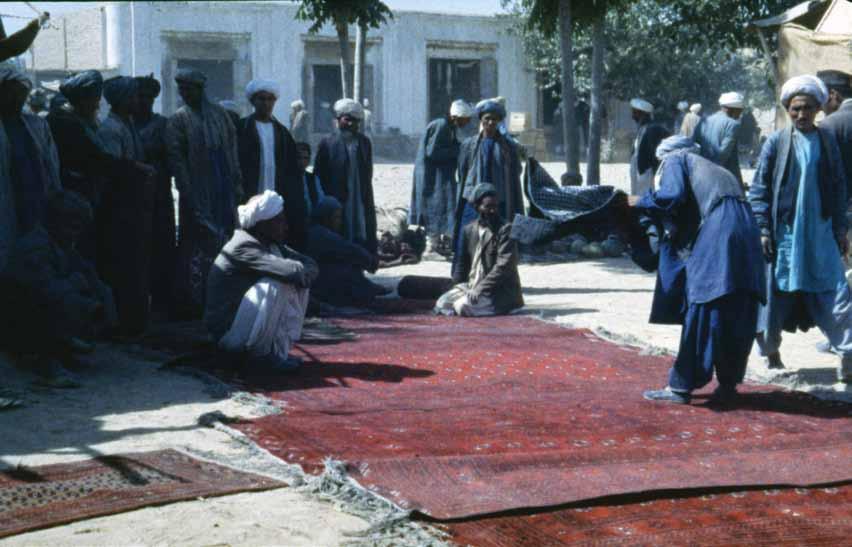 In a rural bazaar, Afghan men look at various oriental rugs. (Daulatabad, Afghanistan, August 1972) interest of collectors moved down-market, it turned by degrees to different types of tribal rugs.