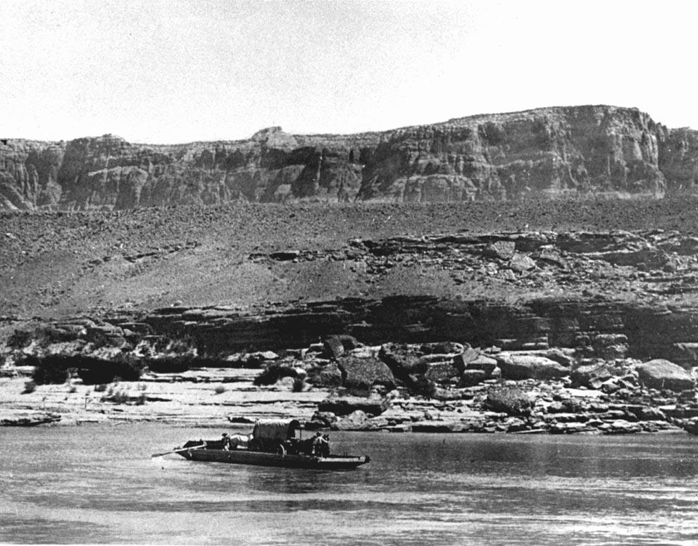 A covered wagon, stock and two men are ferried across the Colorado River on a skow at Lee s Ferry in 1900. Photo F. H.