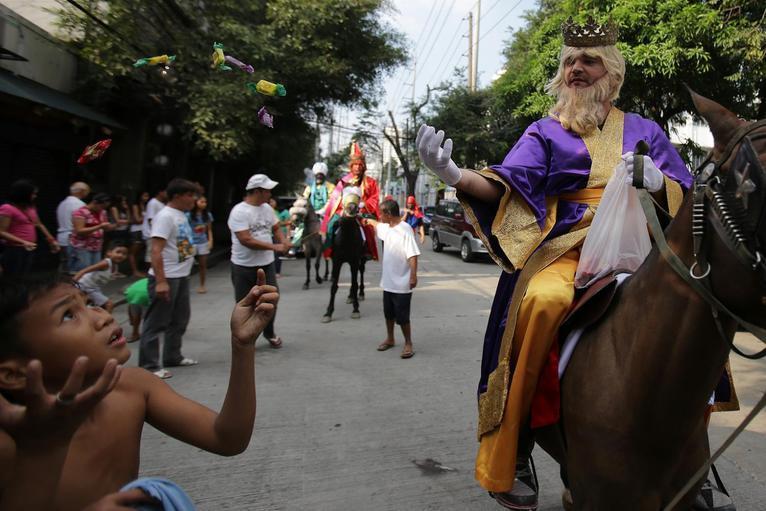 Manila, Philippines Men on horses dressed as the Three Kings throw candy to