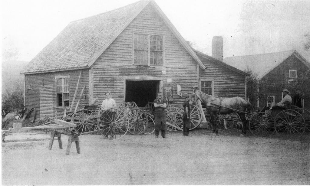 Harley A. Rowe (arms folded) in front of his blacksmith and wheelwright shop Around 1919, Harley's son-in-law, Earle E.