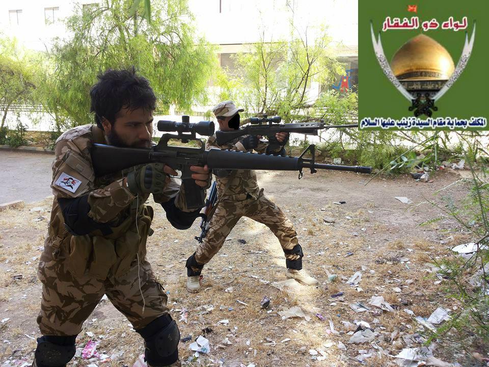 Figure 4: Abu Jafar al- Assad takes aim with an M16A1 style rifle. Another LZ/LAFA militiaman also takes aim with an FN FAL. A Bashar al- Assad patch is fastened to Abu Jafar s arm.