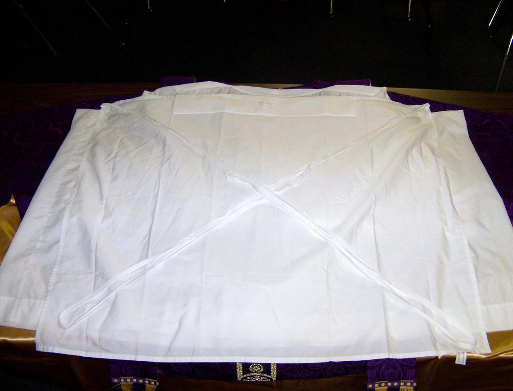 The alb is laid on top of is... And finally e amice. Instead of e chasuble, e deacon puts on his dalmatic.