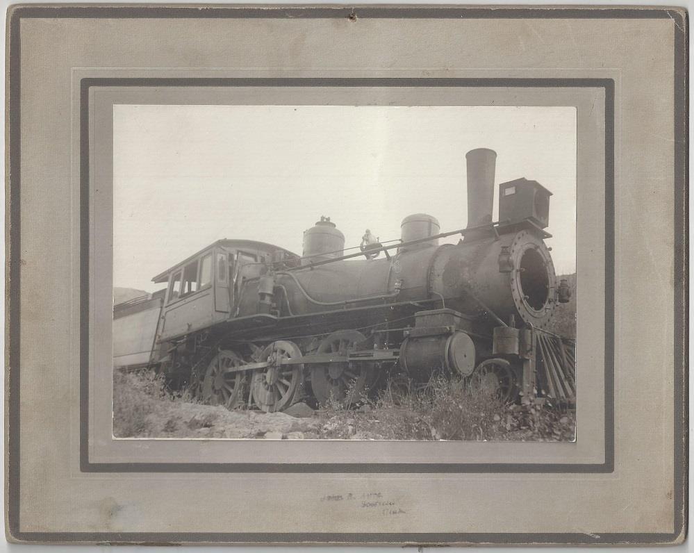 Abandoned Scofield 4- Ayre, John R. [Denver & Rio Grande Locomotive]. Scofield, UT: (c.1900). Albumen photograph [12.5 cm x 17 cm] on a gray mount [20 cm x 25 cm] 'John R.