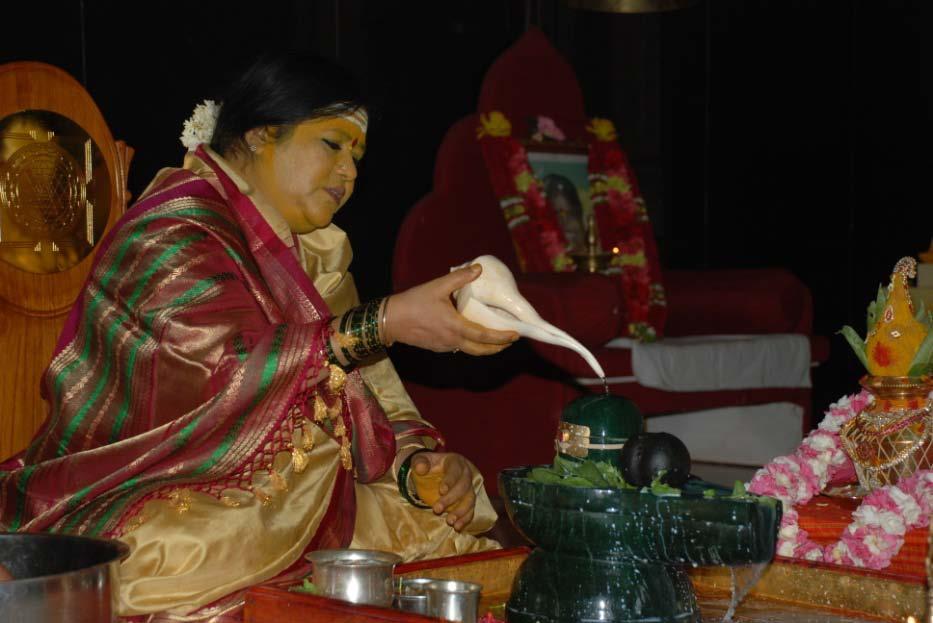 Divine Mother performing abhishekam to a green jade Siva lingam with water from many holy rivers.
